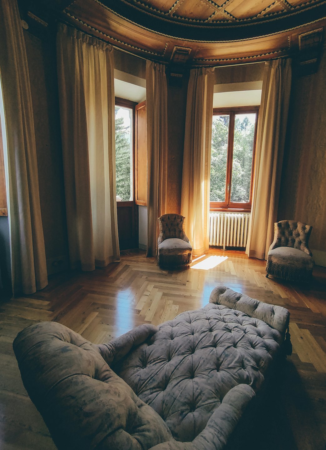 Ornate plafond en parketvloer in een zonnige kamer met chaise longue.