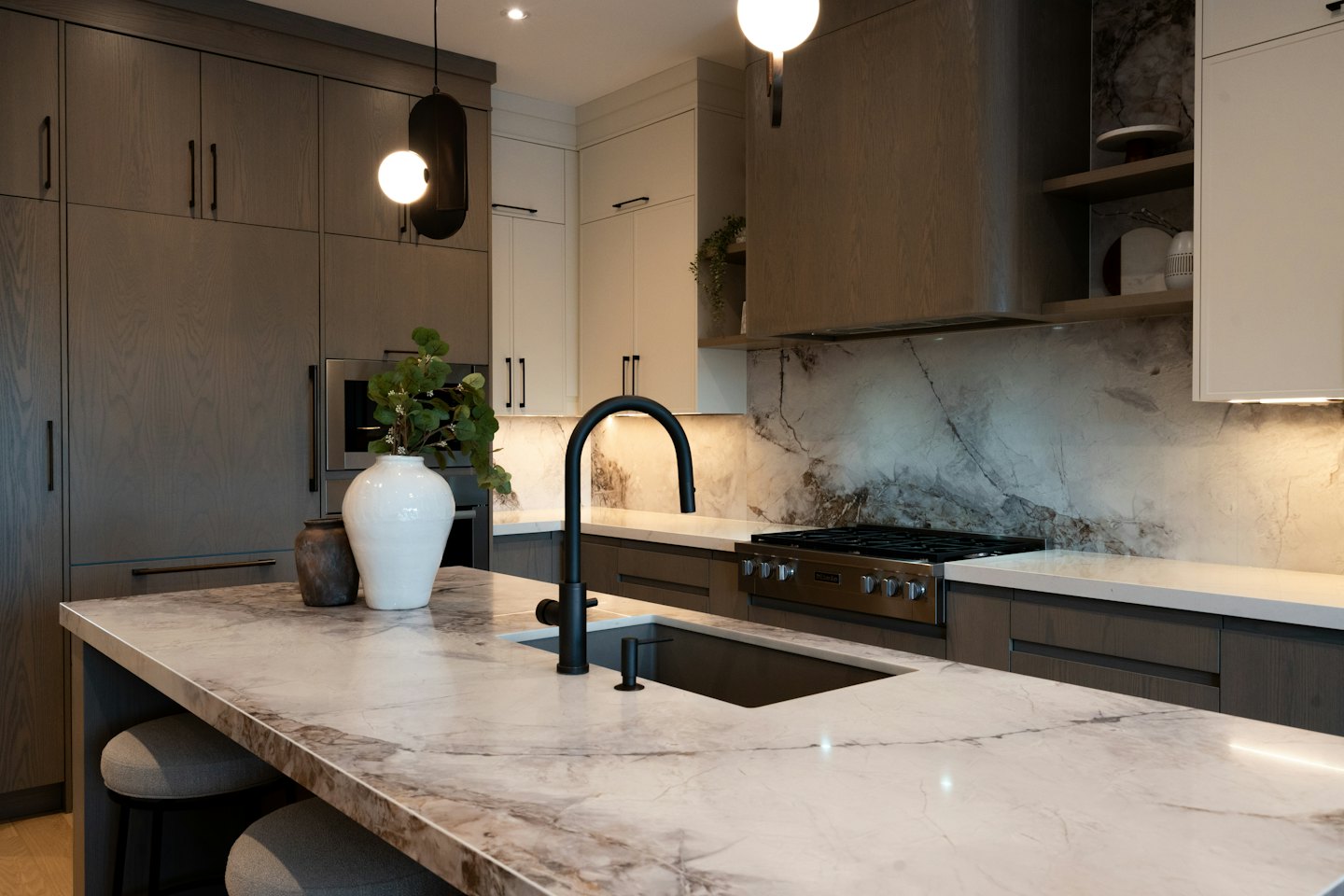 Moderne keuken met marmeren eiland en donkerhouten kasten.